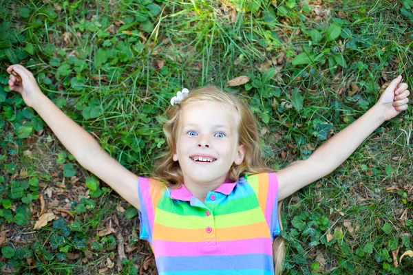 Маленькая забавная девочка, лежащая на траве — стоковое фото