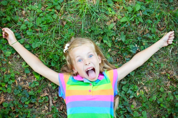 Pequena menina engraçada deitado na grama — Fotografia de Stock