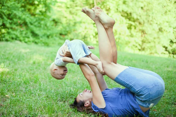 Mãe e filho se divertindo na grama no parque — Fotografia de Stock