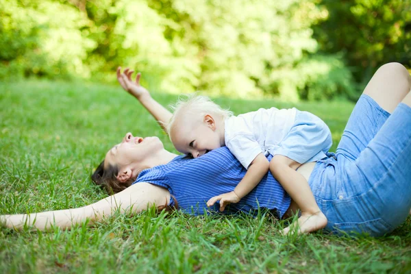 Mãe e filho se divertindo na grama no parque — Fotografia de Stock