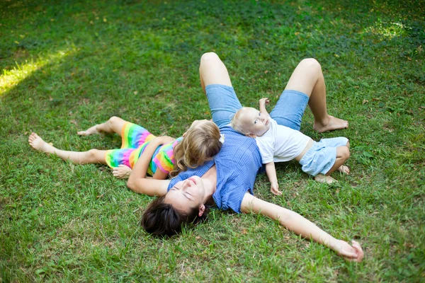 Alegre familia disfrutando de sí mismos acostados en la hierba en el parque —  Fotos de Stock