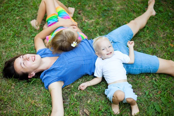 Joyful family enjoying themselves laying on the grass — Stock Photo, Image