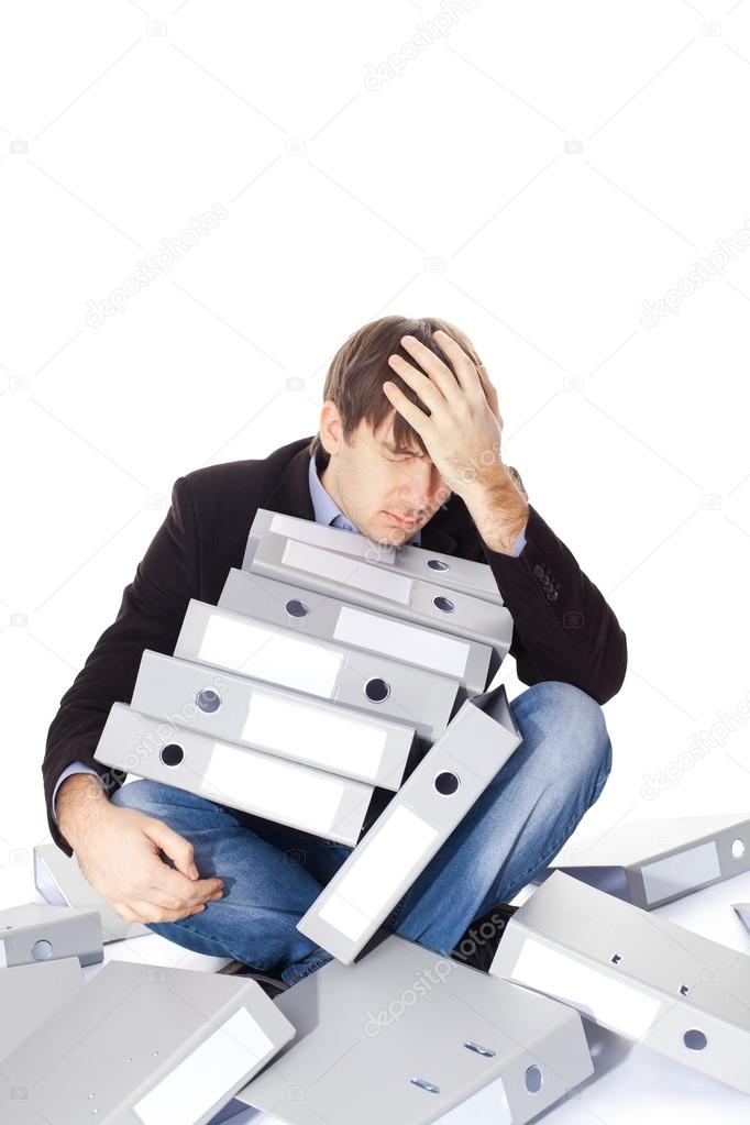 Tired man is sitting with many paper folders isolated on white b