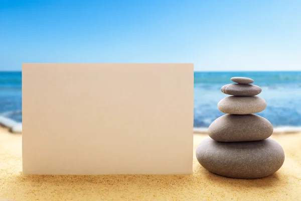 Pyramid of the stones with blank paper on the sandy beach — Stock Photo, Image