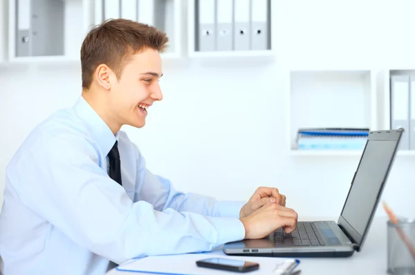 Jovem homem de negócios sorrindo trabalhando no laptop — Fotografia de Stock