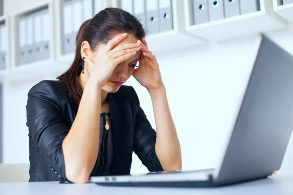 Tired young business woman with laptop at the office — Stock Photo, Image