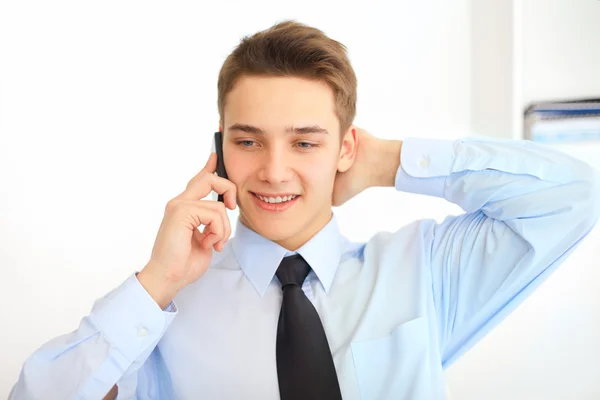 Fiatal mosolygó üzletember mobiltelefonon beszél — Stock Fotó