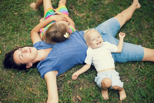 Alegre familia disfrutando de sí mismos acostados en la hierba —  Fotos de Stock