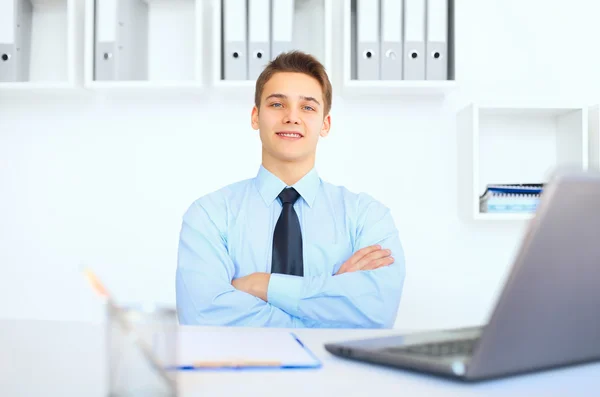 Jovem empresário sorridente em seu local de trabalho no escritório — Fotografia de Stock