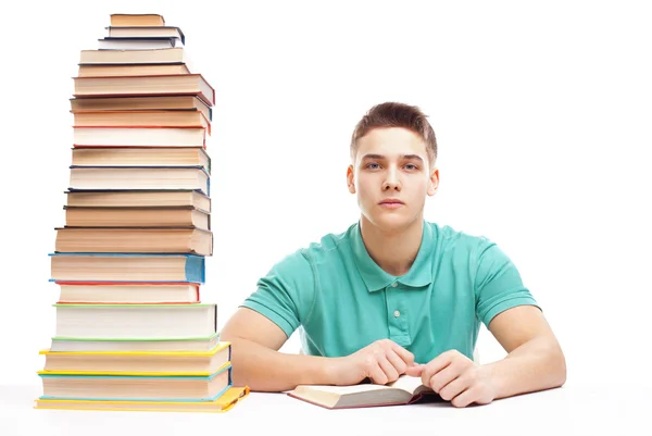 Étudiant étudiant à une table avec une pile de livres élevés — Photo