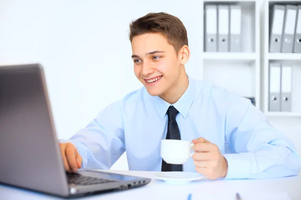 Jovem empresário sorridente com xícara de café no escritório — Fotografia de Stock