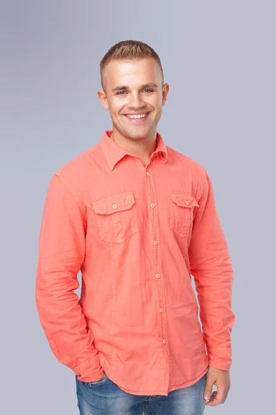 Молодой человек в красной рубашке на сером фоне — стоковое фото