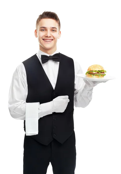 Молодий усміхнений офіціант тримає гамбургер на тарілці — стокове фото