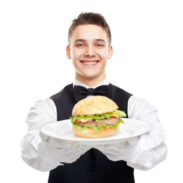 Joven camarero sonriente feliz sosteniendo hamburguesa en el plato — Foto de Stock