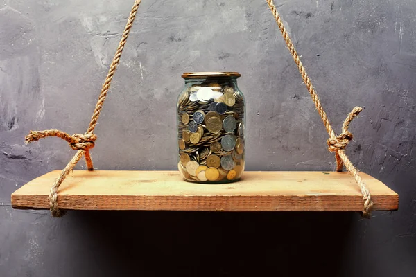 Glass jar with coins on the old wood shelf — Stock Photo, Image