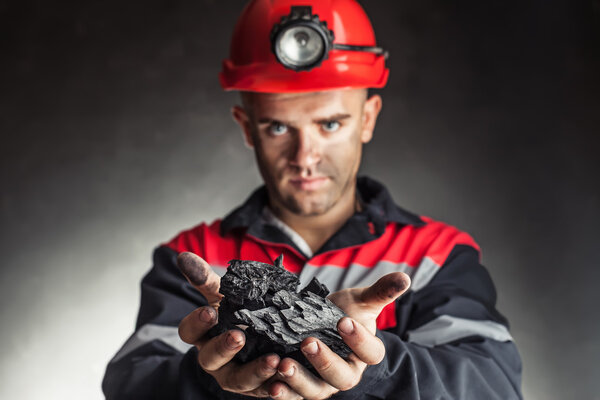 Шахтёр, удерживающий кусок угля
