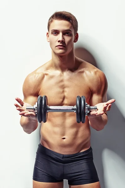 Joven culturista hombre ofreciendo dumbbell — Foto de Stock