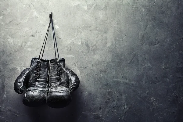 old boxing gloves hang on nail on texture wall