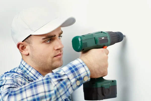 Hombre con taladro haciendo agujero en la pared — Foto de Stock