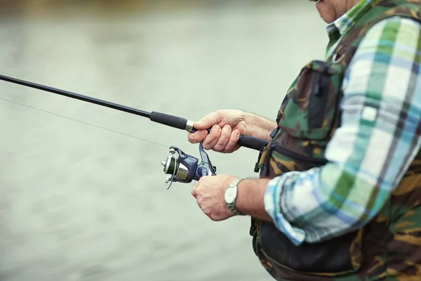 Pescador mão segurando vara de pesca — Fotografia de Stock