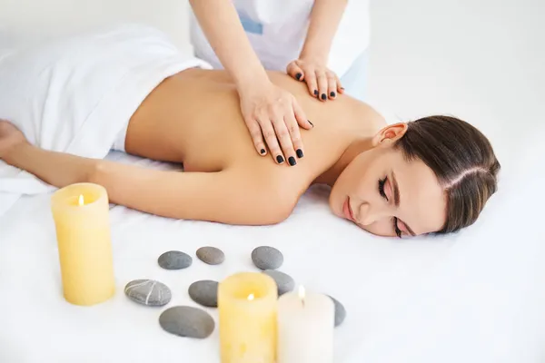 Mladá žena si užívá relaxační masáž zad v lázeňském salonu — Stock fotografie