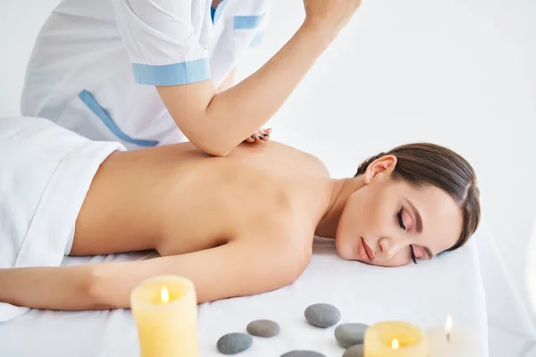 Mladá žena dostává relaxační masáž zad profesionálním terapeutem v lázeňském salonu — Stock fotografie