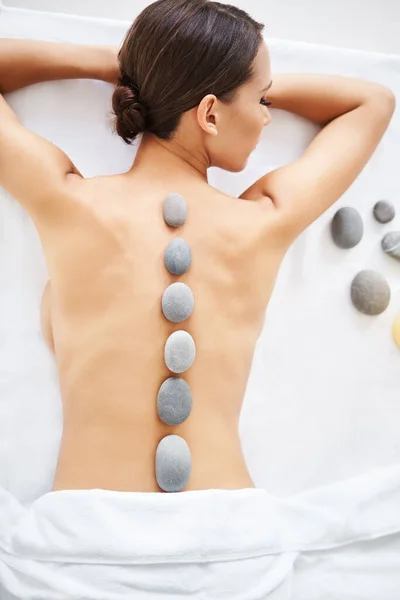 Jong vrouw ontspannen in spa salon met hete stenen op haar rug — Stockfoto