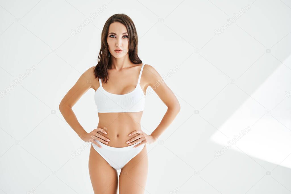 Young and sporty woman in underwear posing on white studio background with copy space