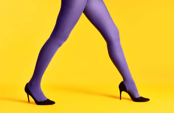 Samice nohy v fialové punčocháče a vysoké podpatky boty na žlutém pozadí — Stock fotografie