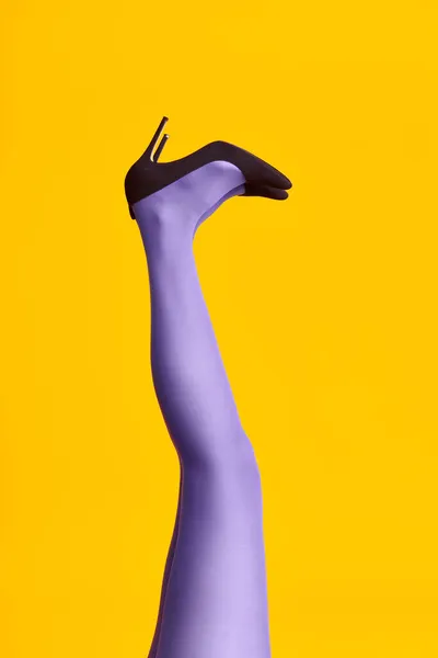 Erhobene Frauenbeine in hellen Strumpfhosen und stylischen High Heels auf gelbem Hintergrund — Stockfoto