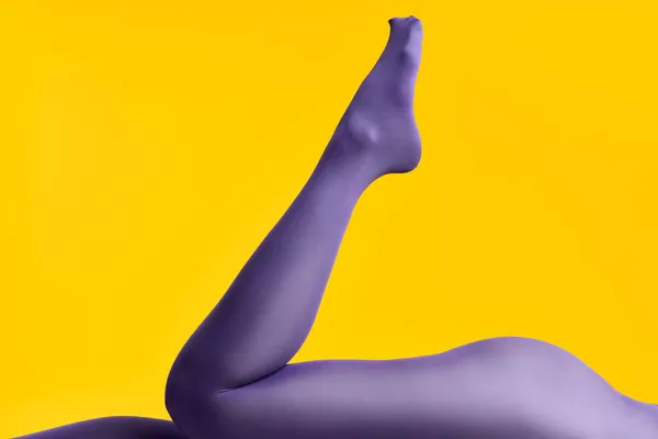 Gambe di bella giovane donna in collant luminosi sdraiato su sfondo giallo — Foto Stock