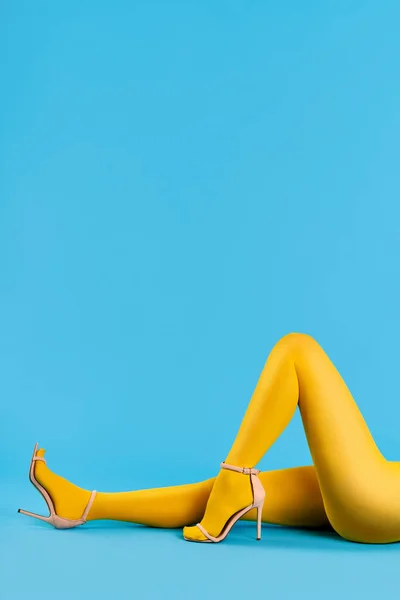 Lábak gyönyörű fiatal nő visel élénk sárga harisnya és magas sarkú cipő fekvő le — Stock Fotó