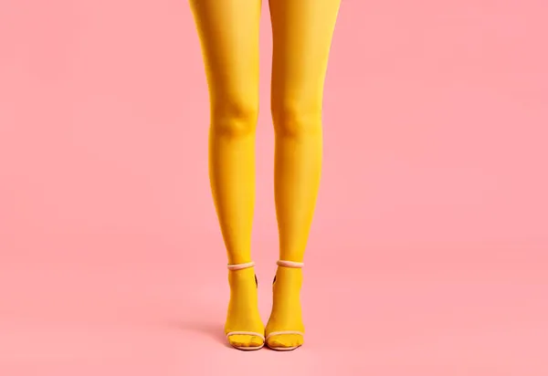 Largas piernas delgadas de mujer joven en medias amarillas y zapatos de tacón alto con estilo sobre fondo rosa. —  Fotos de Stock