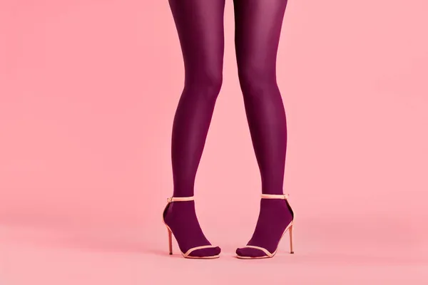 Lange schlanke Beine einer jungen Frau in rosa Strumpfhosen posieren auf rosa Hintergrund — Stockfoto