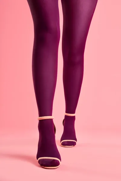 Vista frontal de cerca de las piernas de mujer en medias de color rosa y zapatos de tacón alto con estilo caminando —  Fotos de Stock