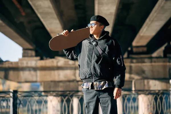 Skater maschio con skateboard in posa su sfondo urbano strada — Foto Stock