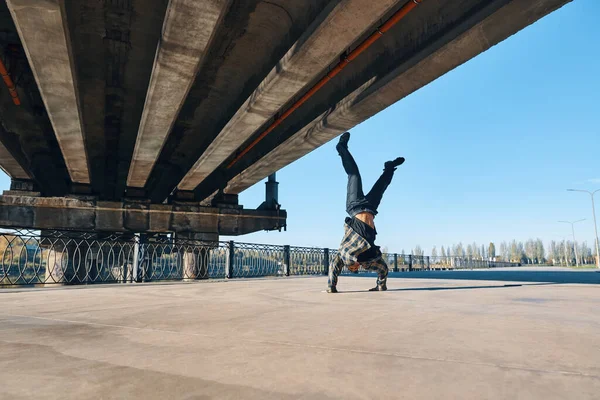 Junger Mann Breakdancer tanzt vor urbanem Hintergrund und vollführt akrobatische Stunts — Stockfoto