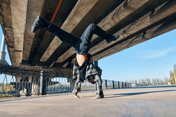 Junger Mann Breakdancer tanzt vor urbanem Hintergrund und vollführt akrobatische Stunts — Stockfoto
