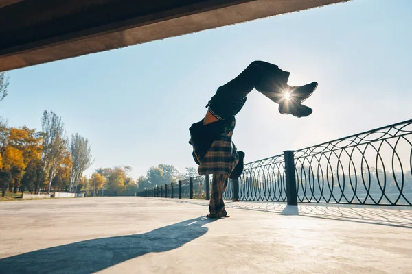 Молодой человек танцует брейк-данс на городском фоне, исполняя акробатические трюки — стоковое фото
