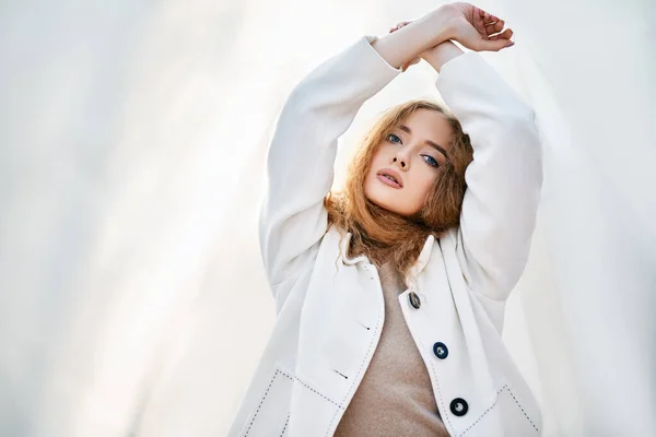 Jovem mulher atraente em roupas brancas posando no fundo pálido abstrato olhando para câmera confiante — Fotografia de Stock