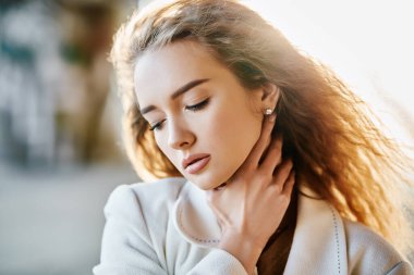 Güneşli bir günde şehir arka planında kameraya bakan güzel, şehvetli bir kadının yakın plan portresi.