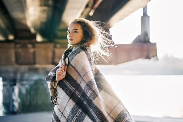 Retrato de mujer bastante confiada envuelta en manta de lana mirando a la cámara posando sobre fondo urbano de calle con espacio de copia — Foto de Stock