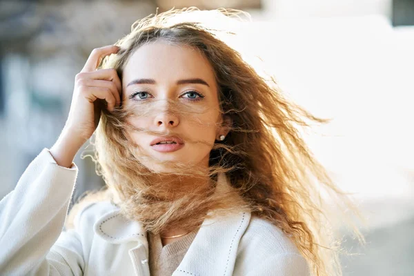 Güneşli bir günde şehir arka planında kameraya bakan güzel, şehvetli bir kadının yakın plan portresi.