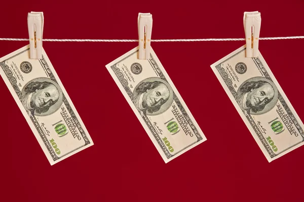 Money laundering, US dollars hanging on rope over red studio background — Stock Photo, Image