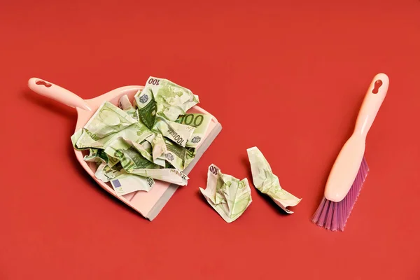 Creative layout with dustpan, hand brooms and crumpled money dollar bills on red background — Stock Photo, Image