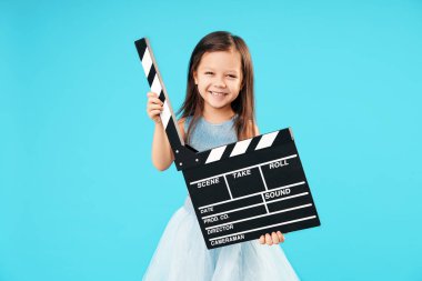 Lovely smiling little girl holding directors film movie slateboard