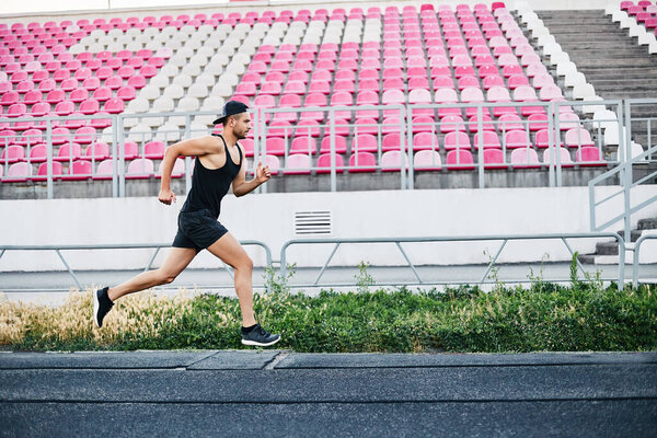 Athlete man running on the running track over empty seats in a sport stadium Stock Photo