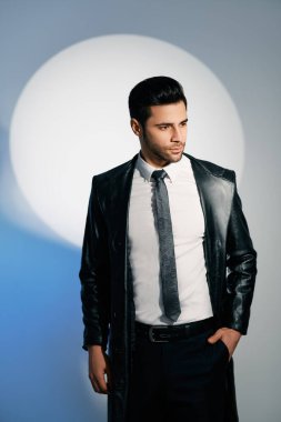 Stüdyonun arka planında spot ışıkları altında poz veren yakışıklı moda adamı.