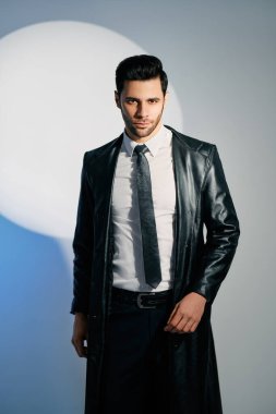 Stüdyonun arka planında spot ışıkları altında poz veren yakışıklı moda adamı.