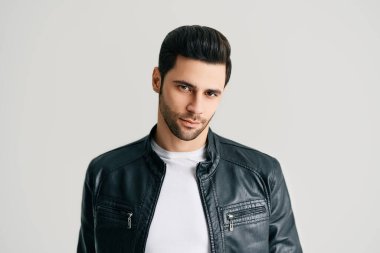 Beyaz stüdyo arka planında poz veren yakışıklı adamın yakın plan portresi.